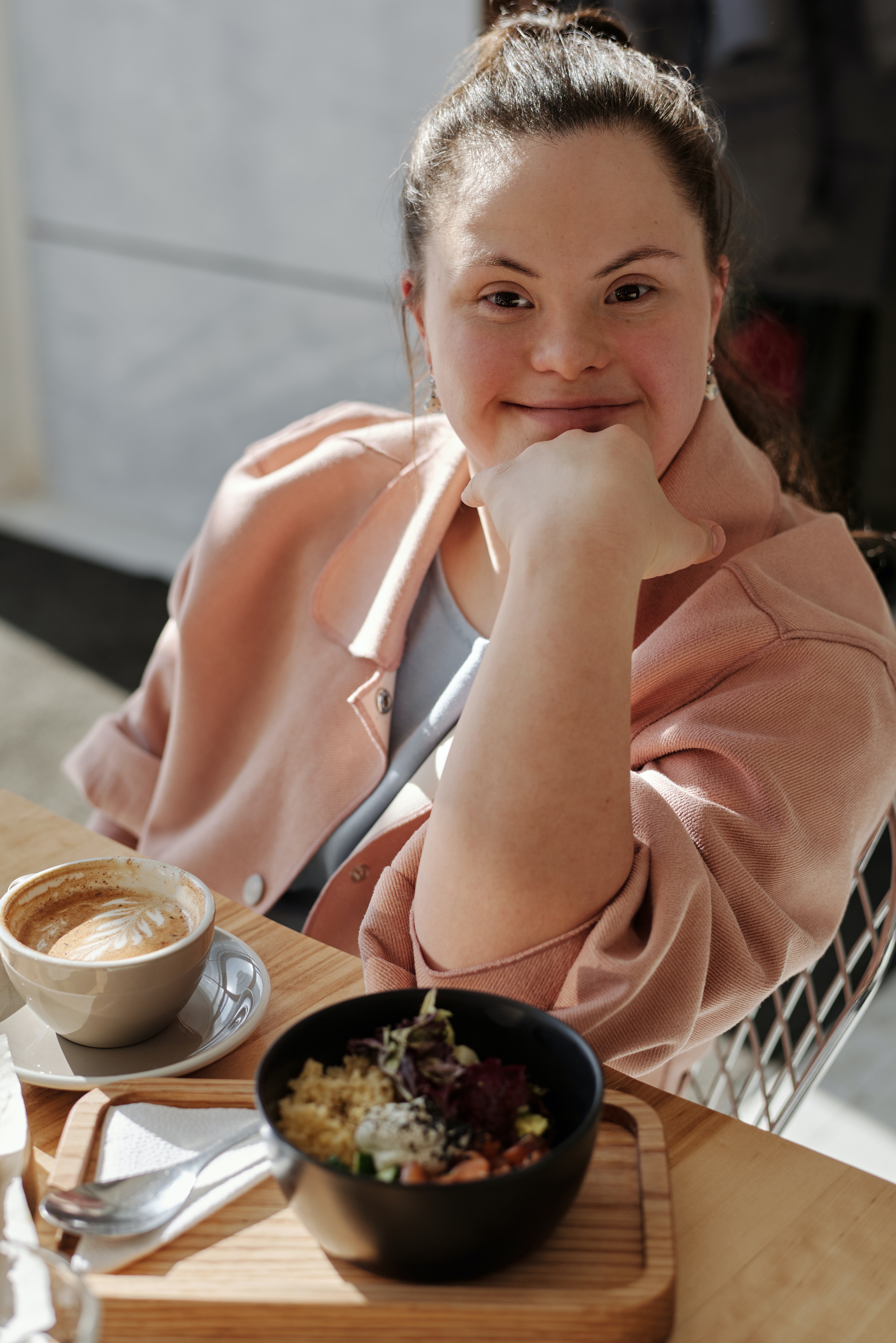 Betreuung von Menschen mit Behinderung Thun: Glücklich wirkende Frau mit Trisomie 21 an Kaffeetisch